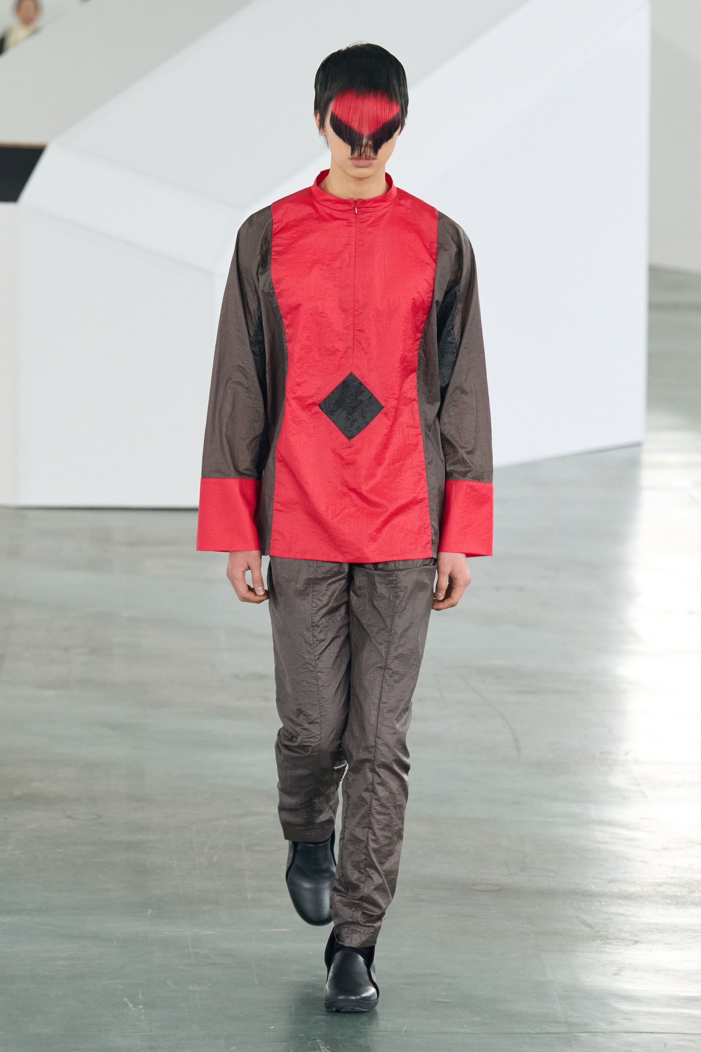 Kiko Kostadinov 26FW 继续深化其结构语言，以功能主义为表象，内核却极度诗性。不对称剪裁、分割式廓形与工业面料共同构建出一种“行走中的系统服装”。红黑配色与面部遮挡强化仪式感，使服装看似冷静却暗含张力。Kiko 的设计始终拒绝讨好市场，而是为思想型穿着者构建独立审美秩序-顽石频道趋势研究